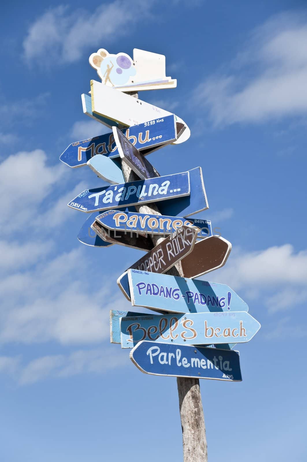 Close-up on lot of signs in only one roadsign to the world surf spots on a beach with a blue sky