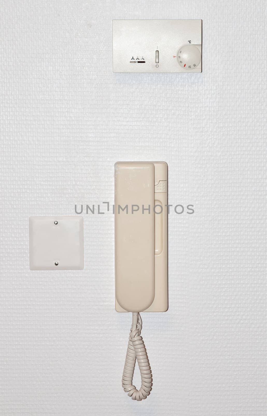 Beige intercom on a white wall with an air conditioning adjuster