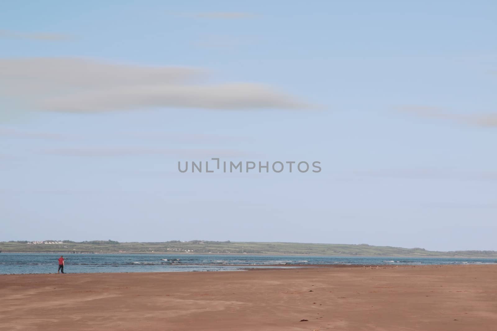 man walking on beale beach co kerry ireland on a cold winters morning with turbines in the background
