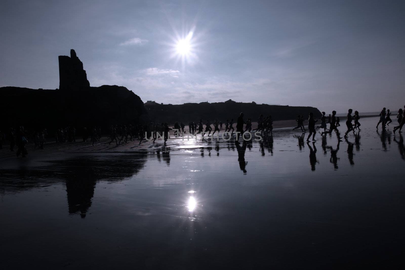people some dressed in santa hats doing a christmas swim for charity with castle in background
