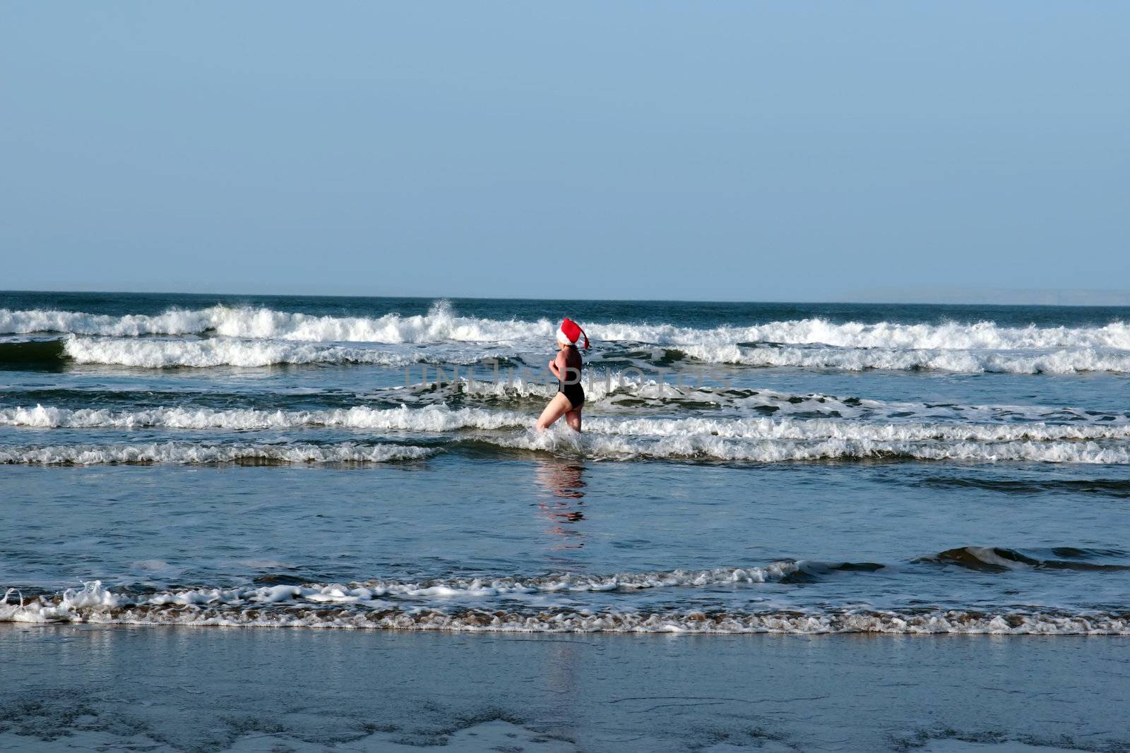 woman dressed in santa hat doing a christmas swim for charity