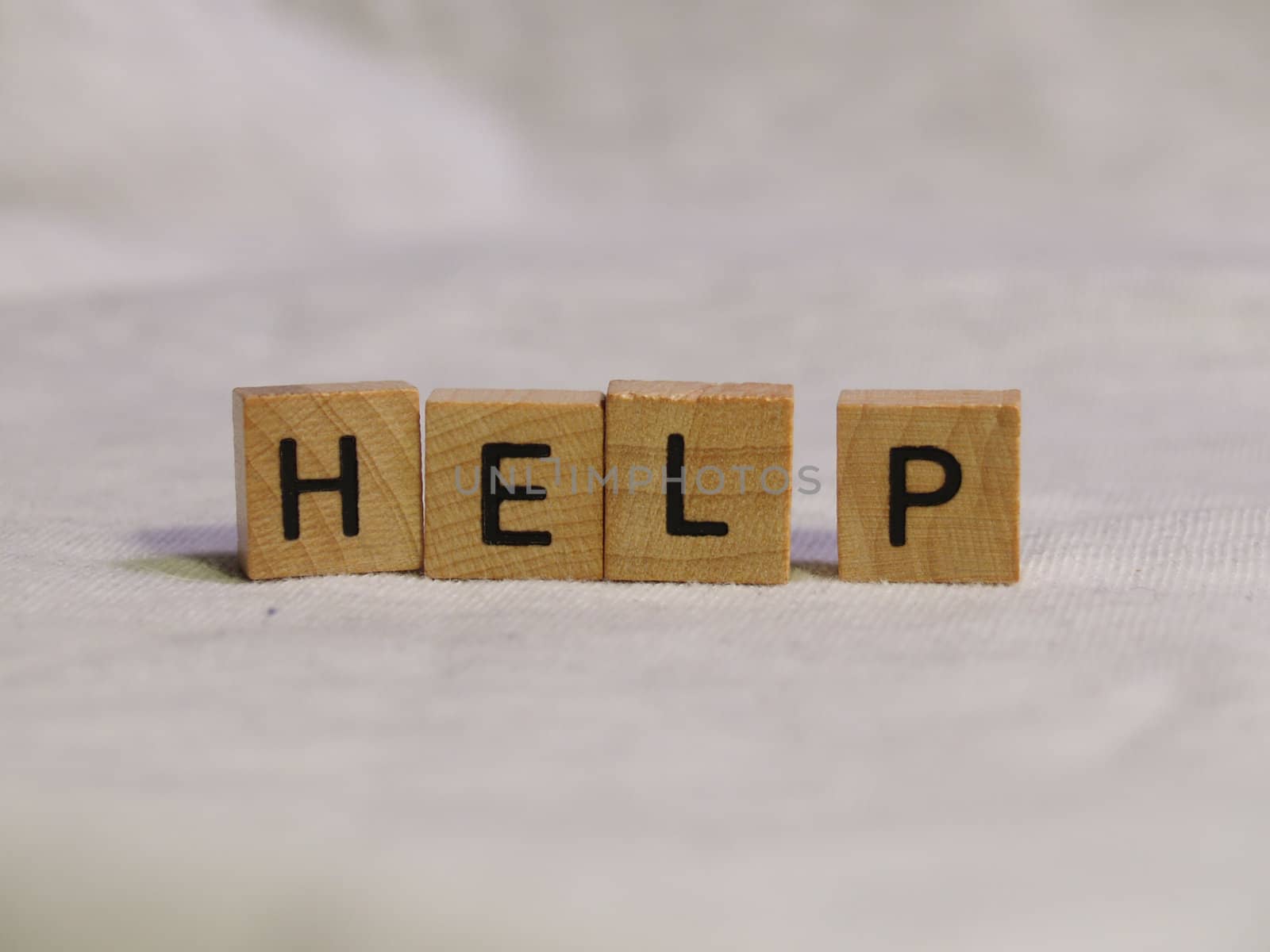 The word HELP spelled out with wooden tiles