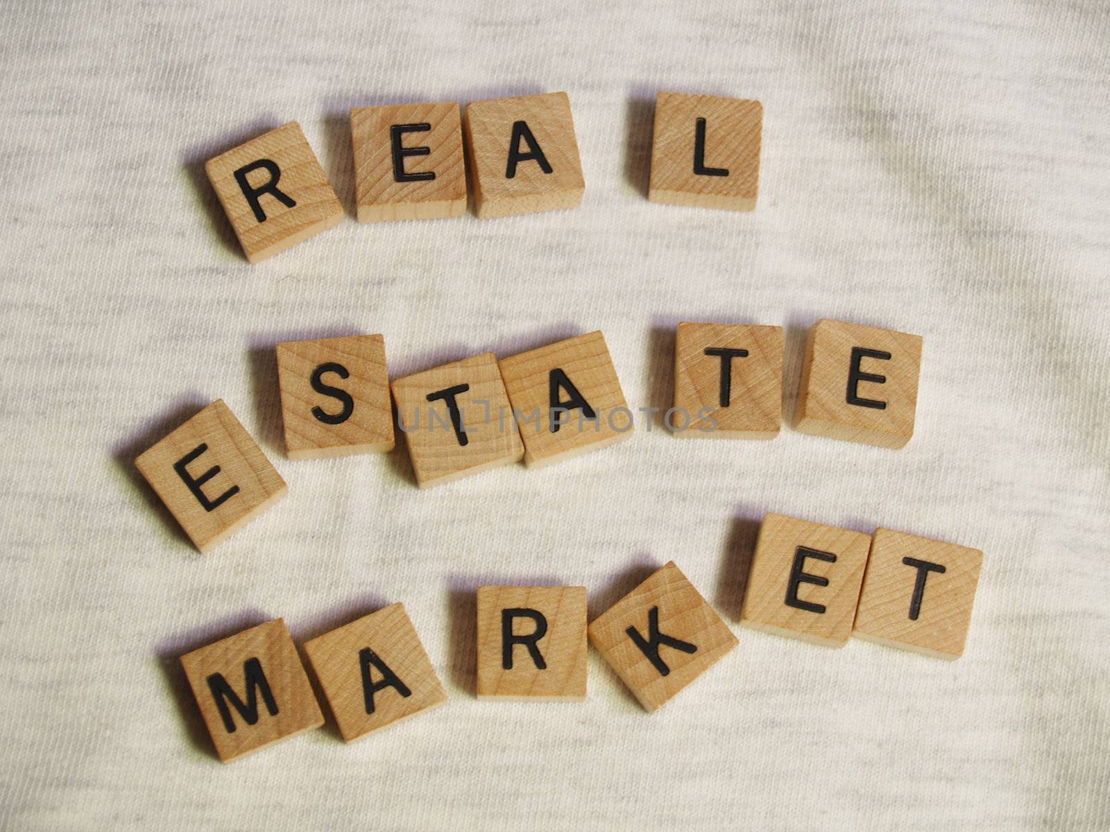 The words REAL ESTATE MARKET spelled out with scattered wooden tiles