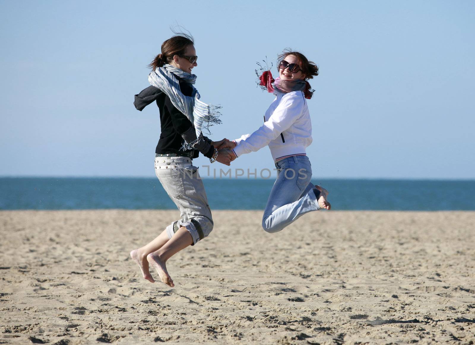 Two happy jumpers girl on the beach. Atlantic coast. France