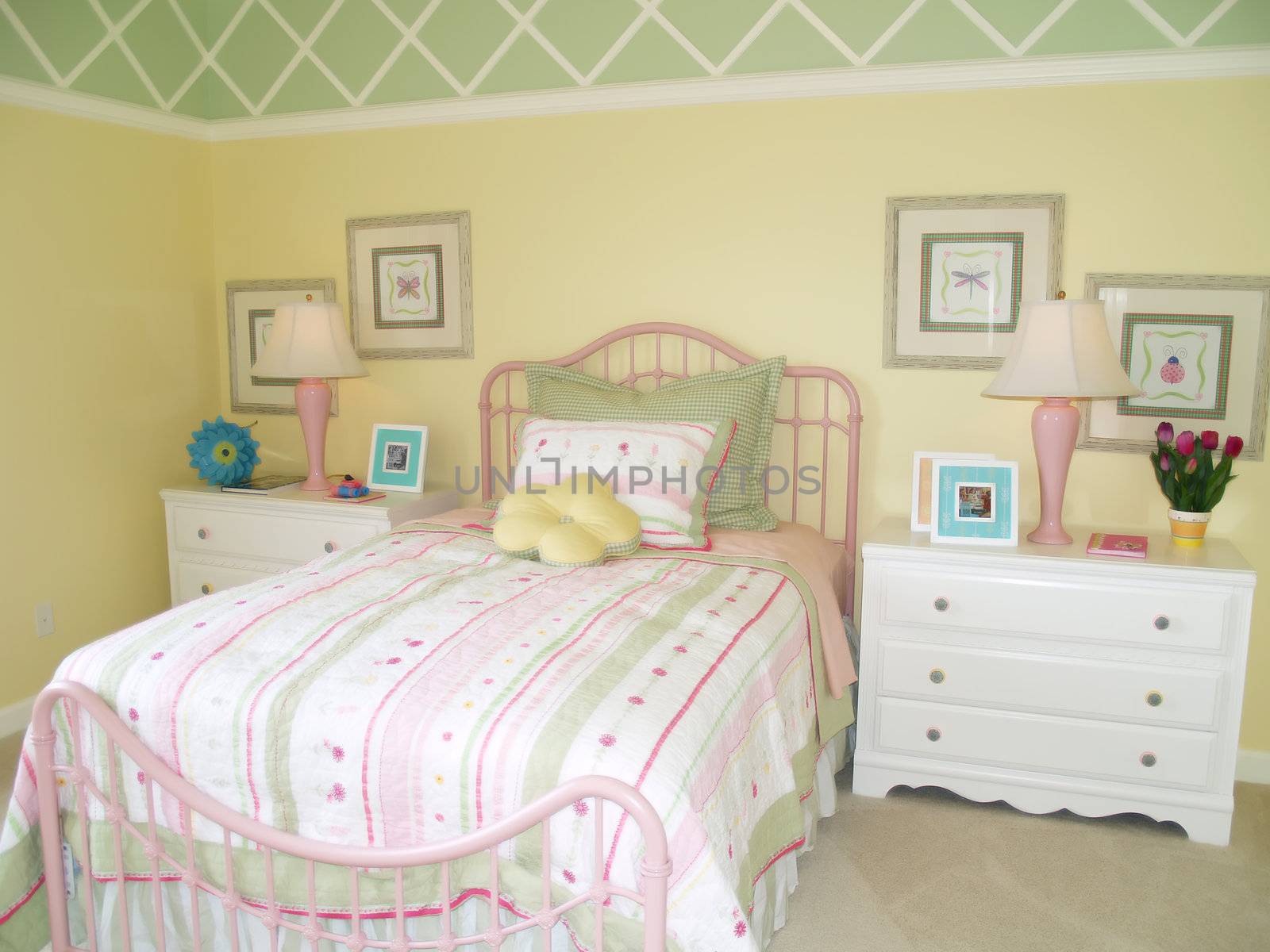 Bright yellow children's bedroom tastefully decorated with a green diamond border at the ceiling. 