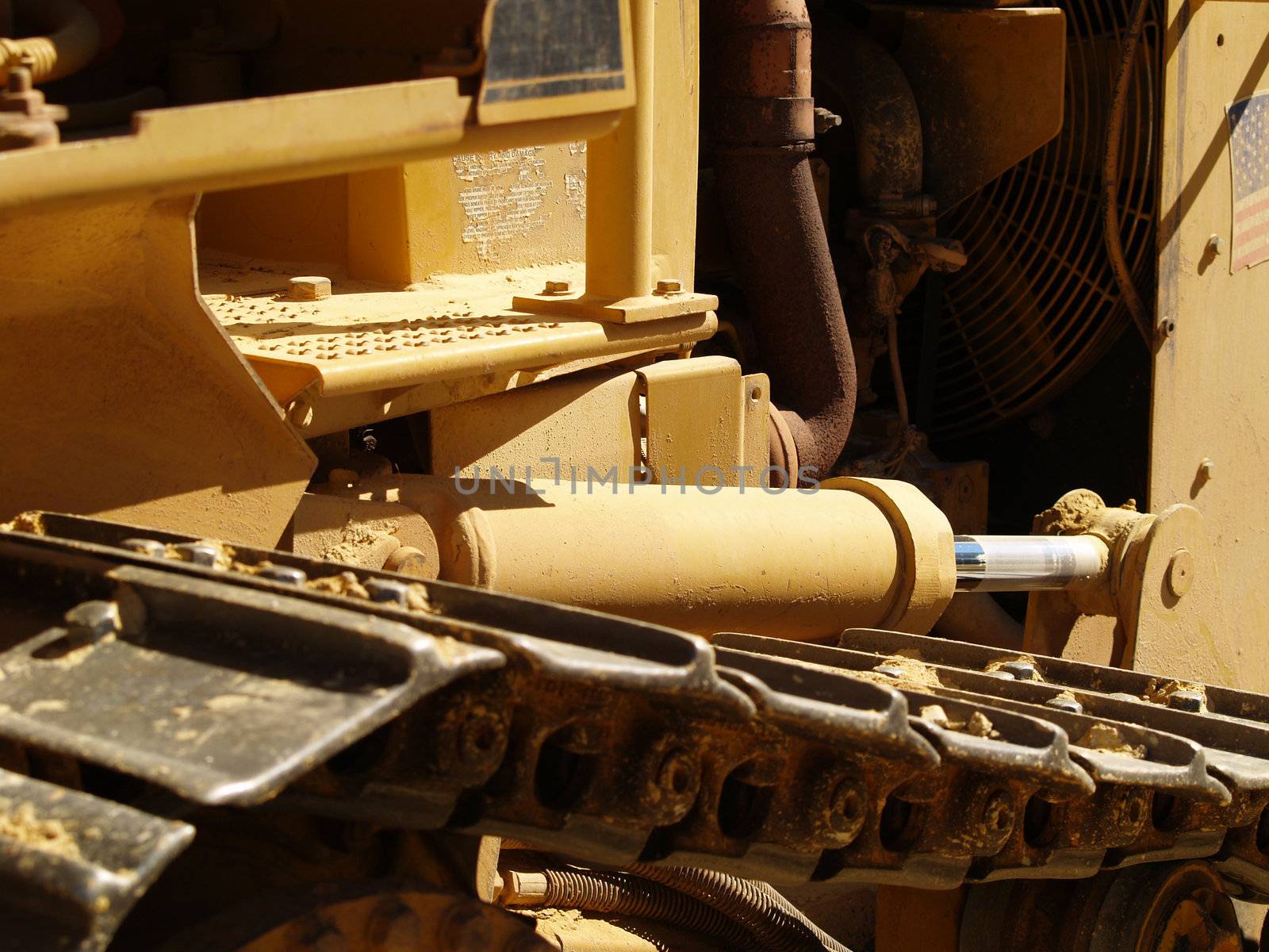 Closeup of the side of a heavy equipment earth moving bulldozer on a dusty construction site.