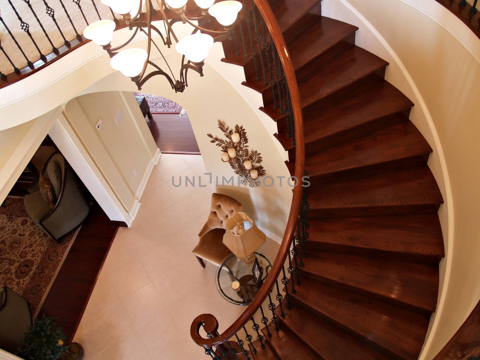 Interior view of a foyer with curving staircase, tiled floors and furniture