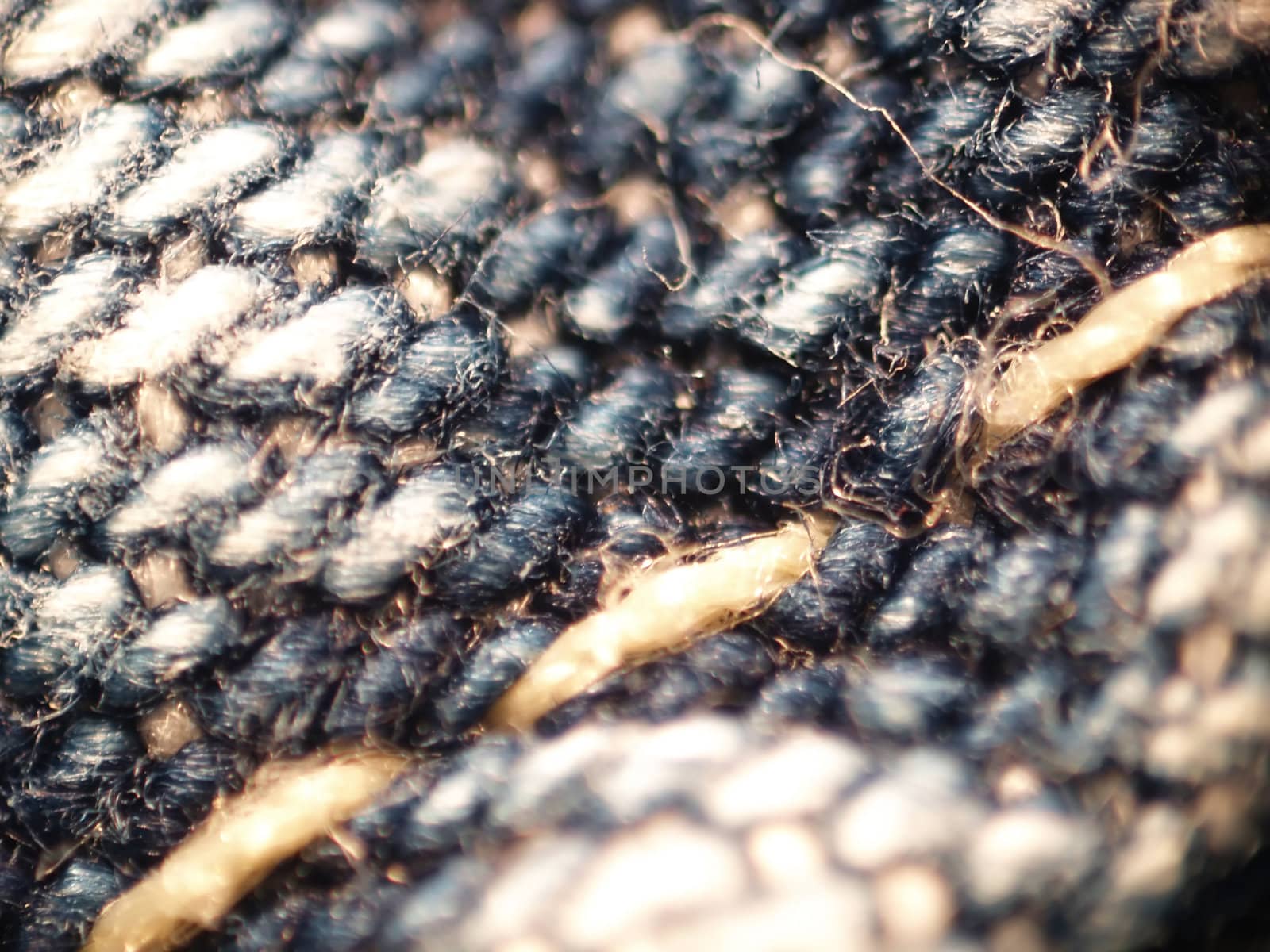 Macro of three stitches of thread in denim fabric