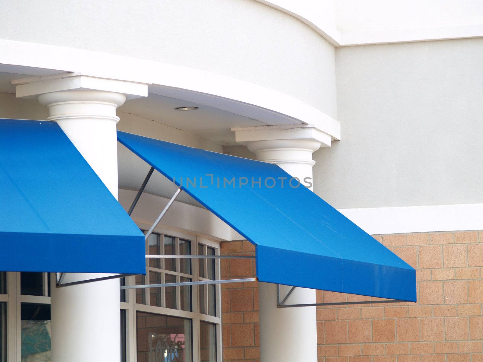 Two blue awnings against a white columned light brick office building
