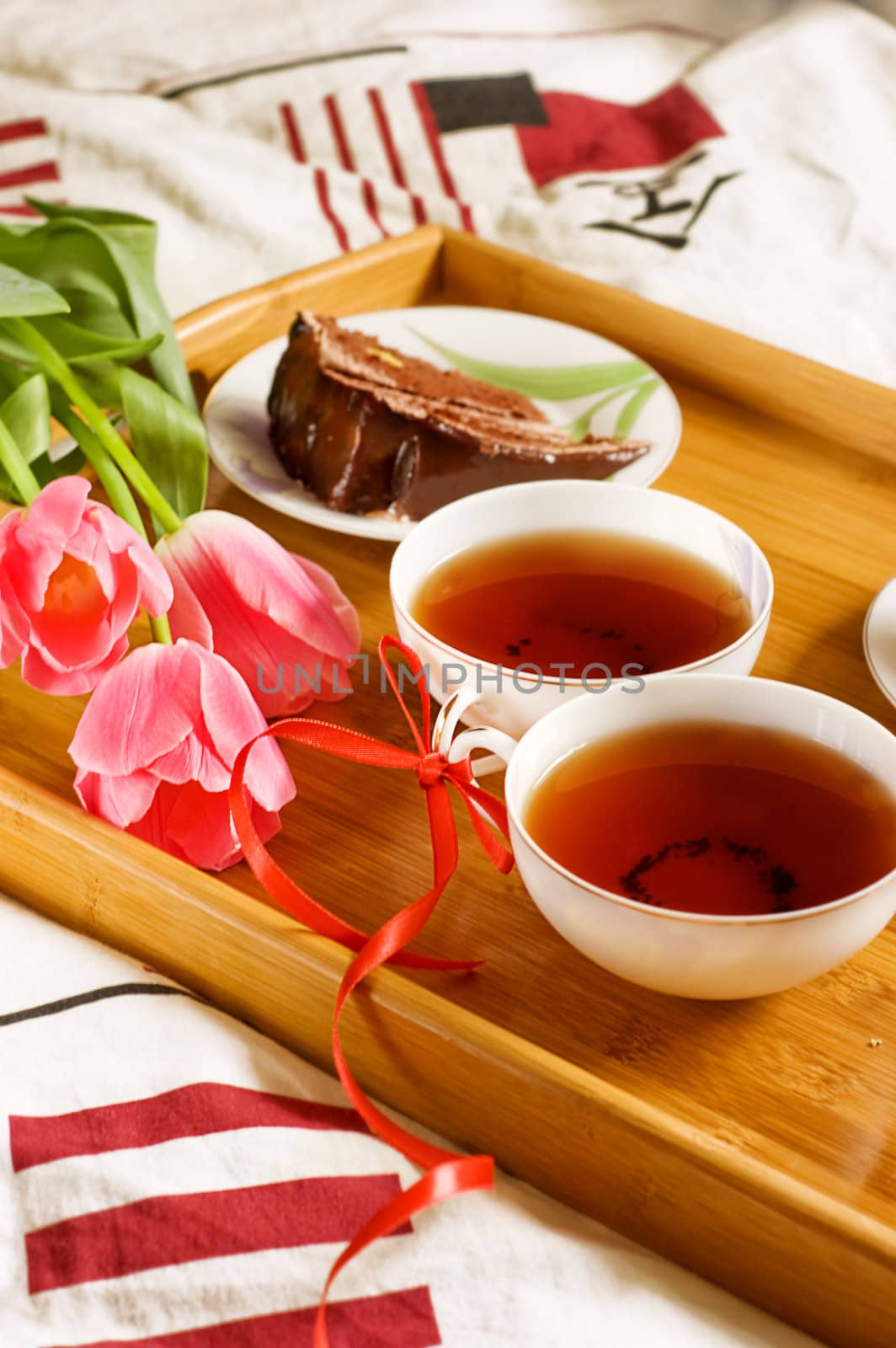Breakfast tray on bed with tea, cakes and tulips