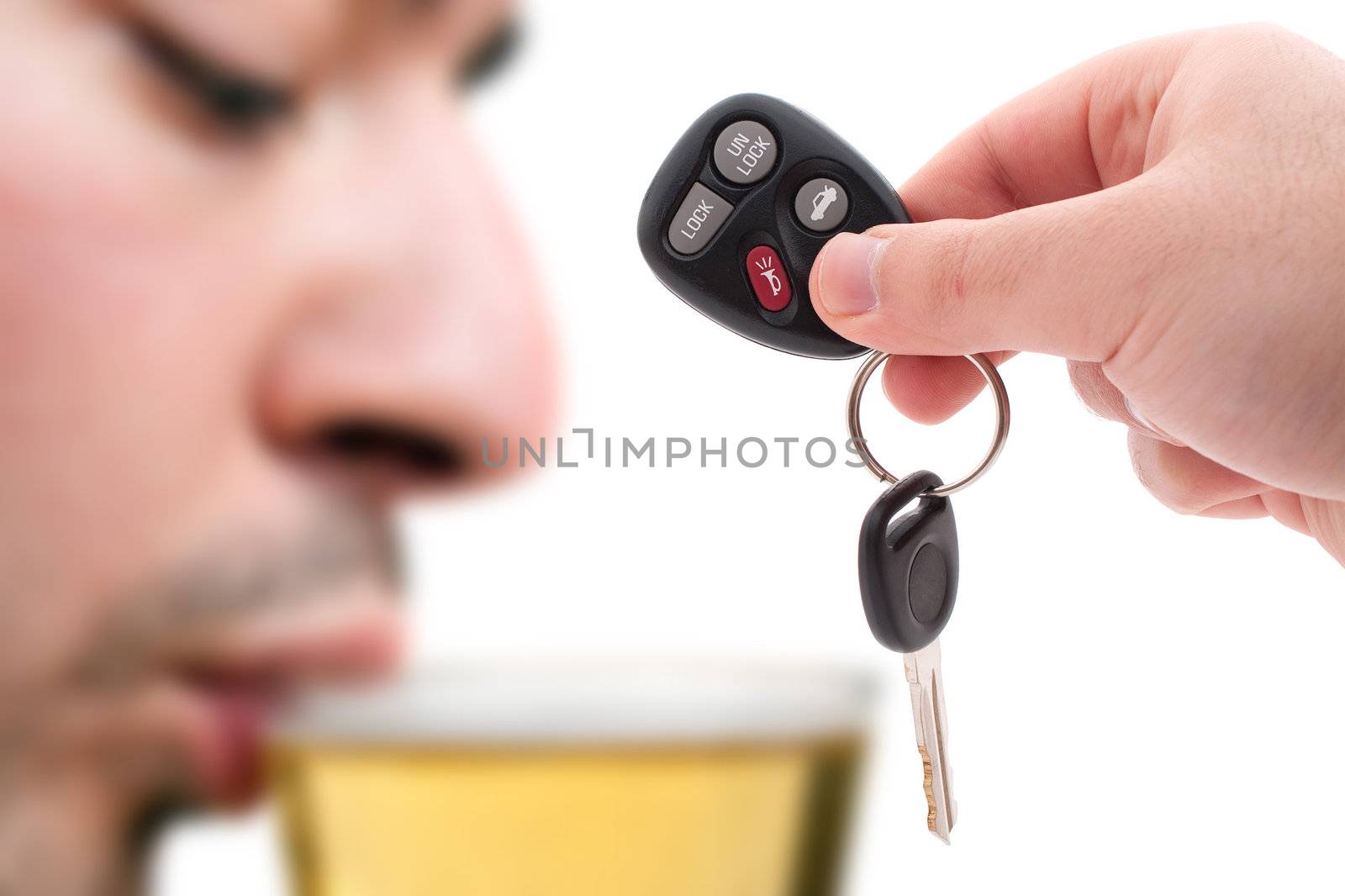 Drunk driving concept with a hand holding some car keys and a man drinking beer in the background.  Shallow depth of field.