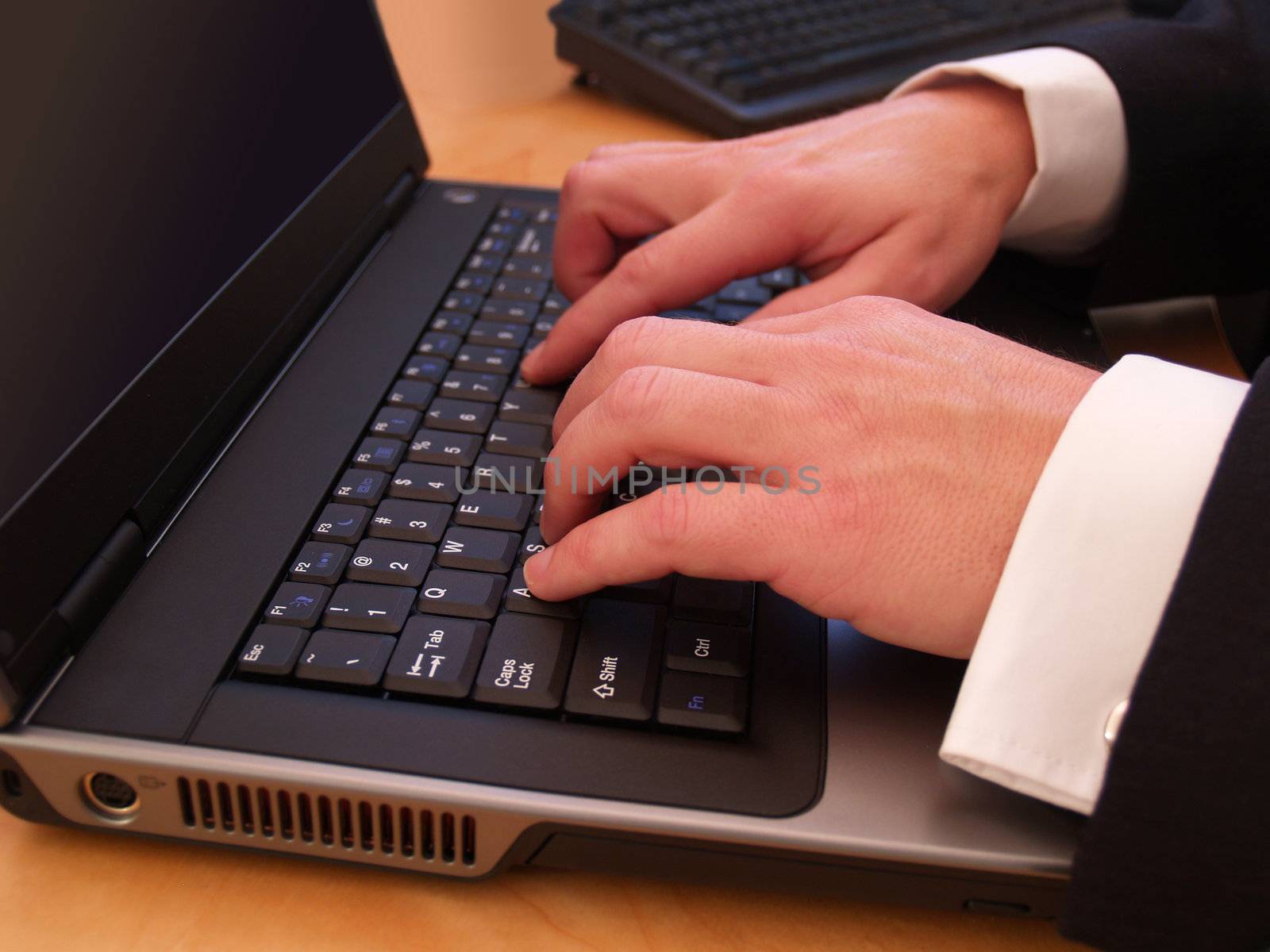 Closeup of a man's hands typing on a laptop