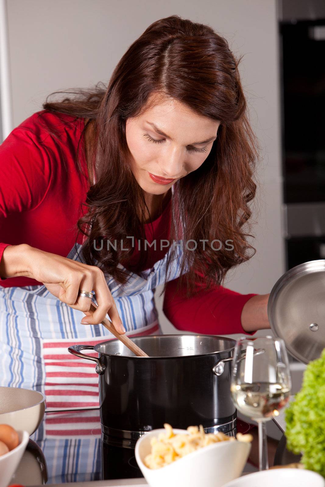 Pretty young woman stirring in the pan of soup