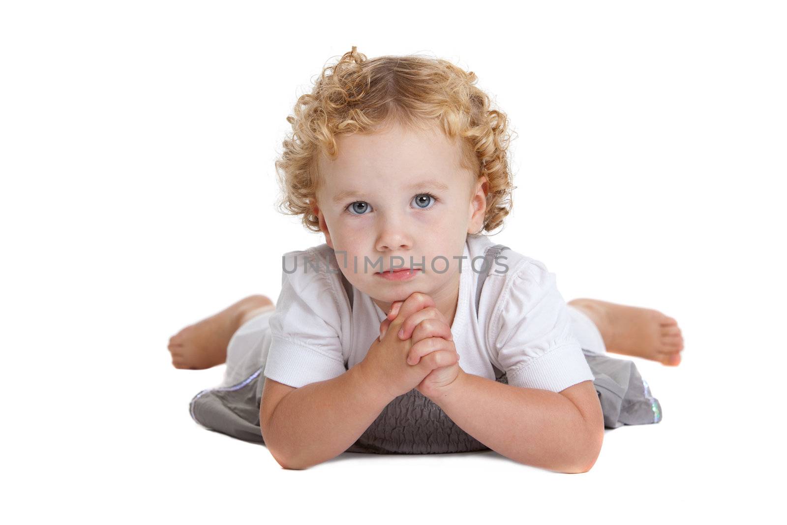 Cute three year old girl lying on the floor and looking serious