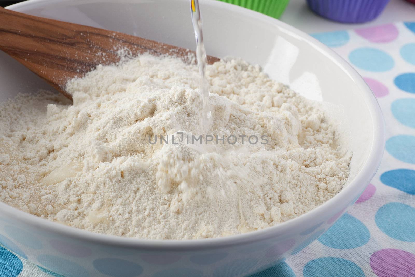 Water being poured into a bowl of flour.