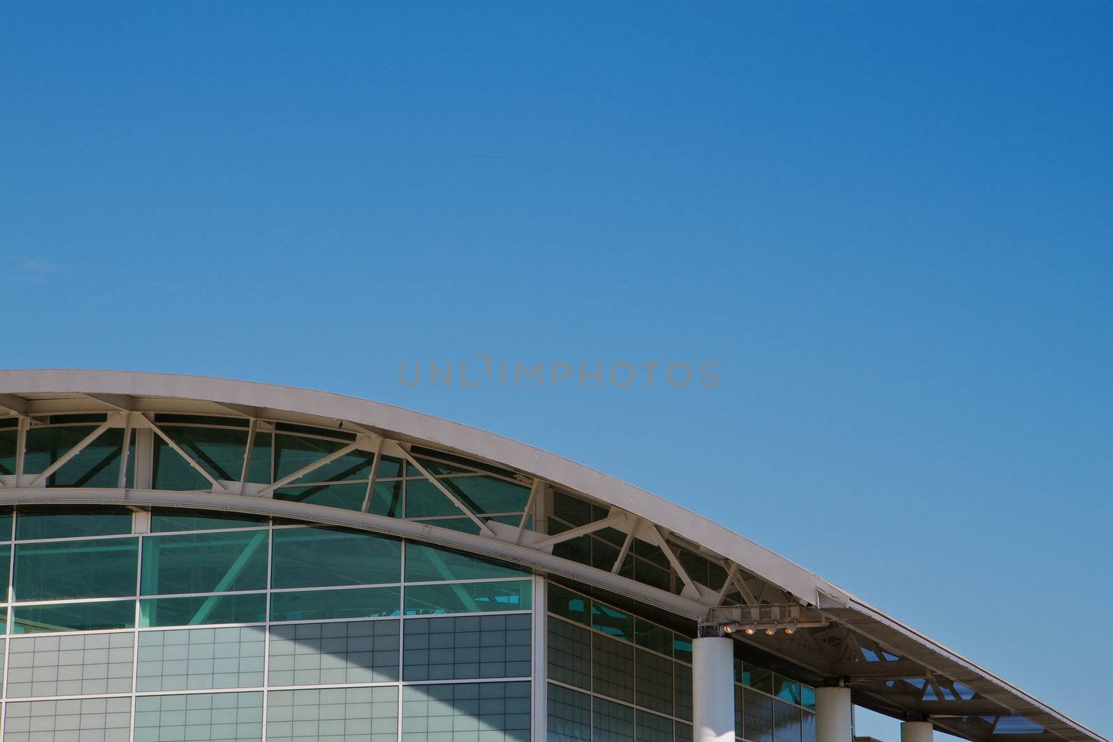 Arched roof sports complex building aginst a cloudless blue sky