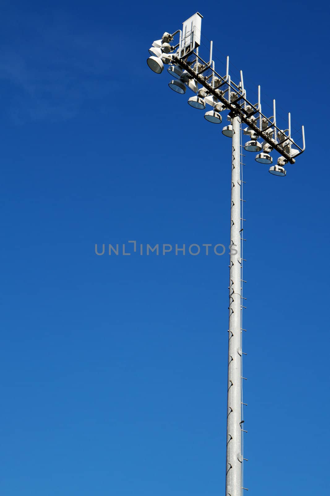Sporting Field lights on top of tall steel pole with dark blue sky background