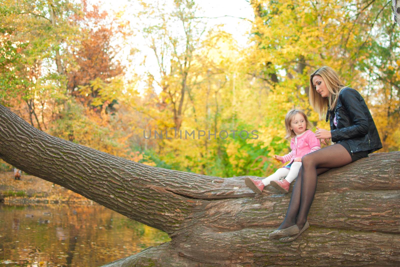 Family pair is sitting on big tree near the pond