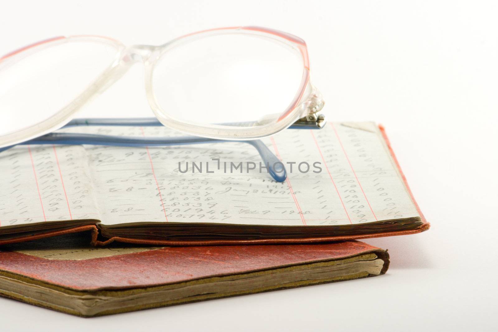 two financial ledgers and a pair of glasses on a white background