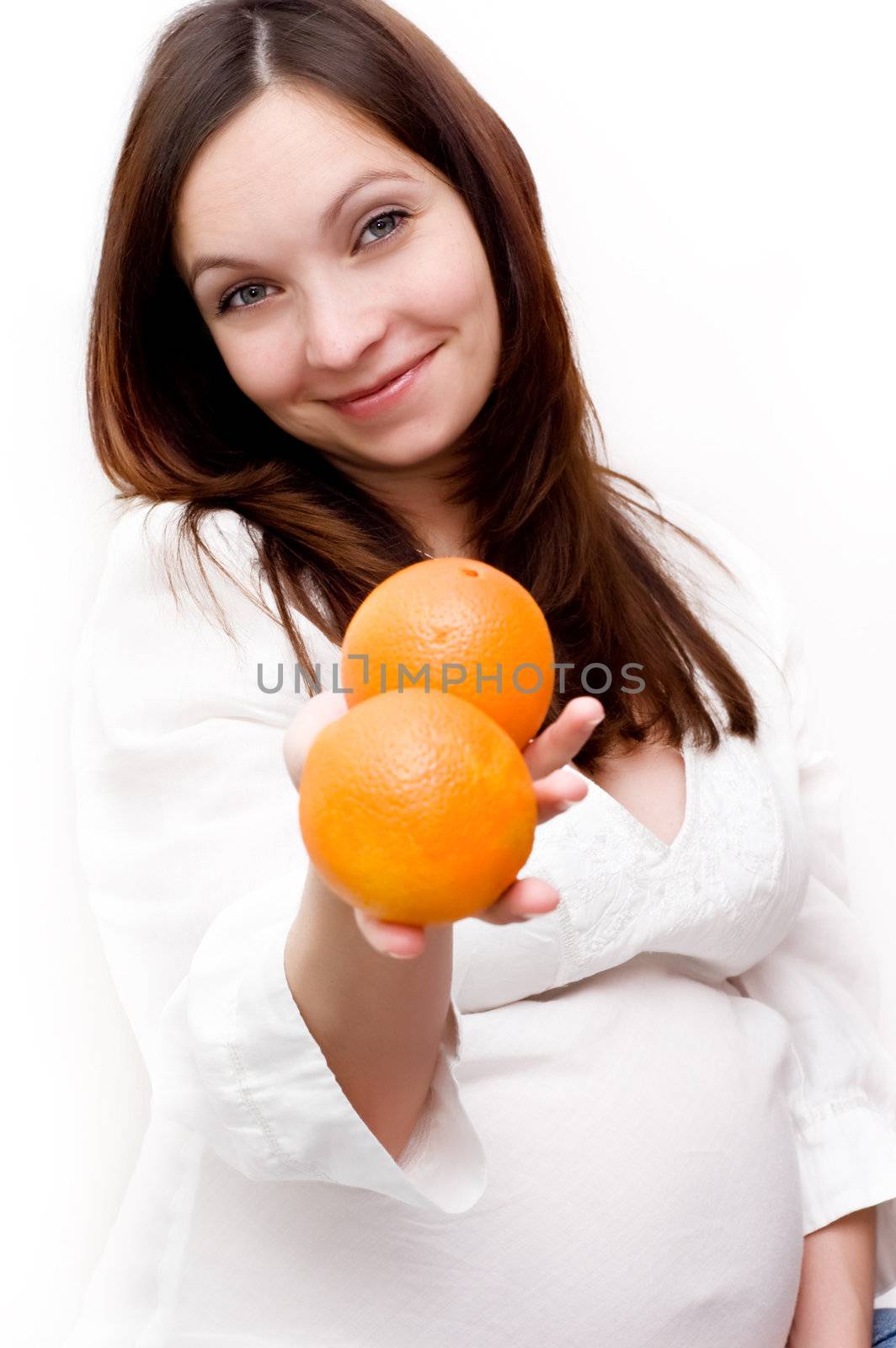 Pregnant woman holding oranges over white