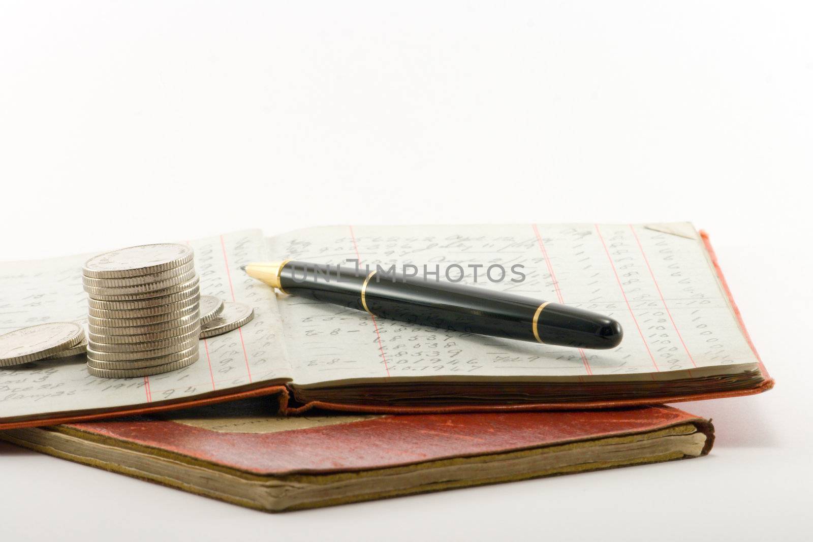 two financial ledgers and a pile of coins on a white background