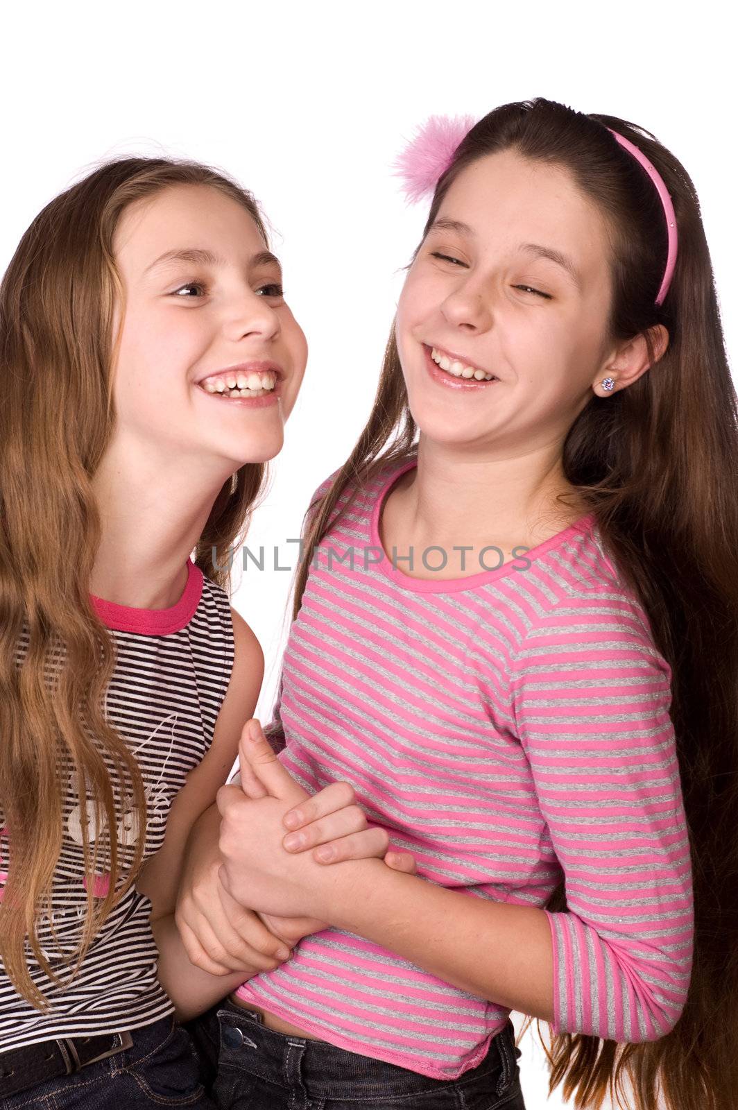 Two girls in the age of ten and eleven laughing and holding their hands isolated on white