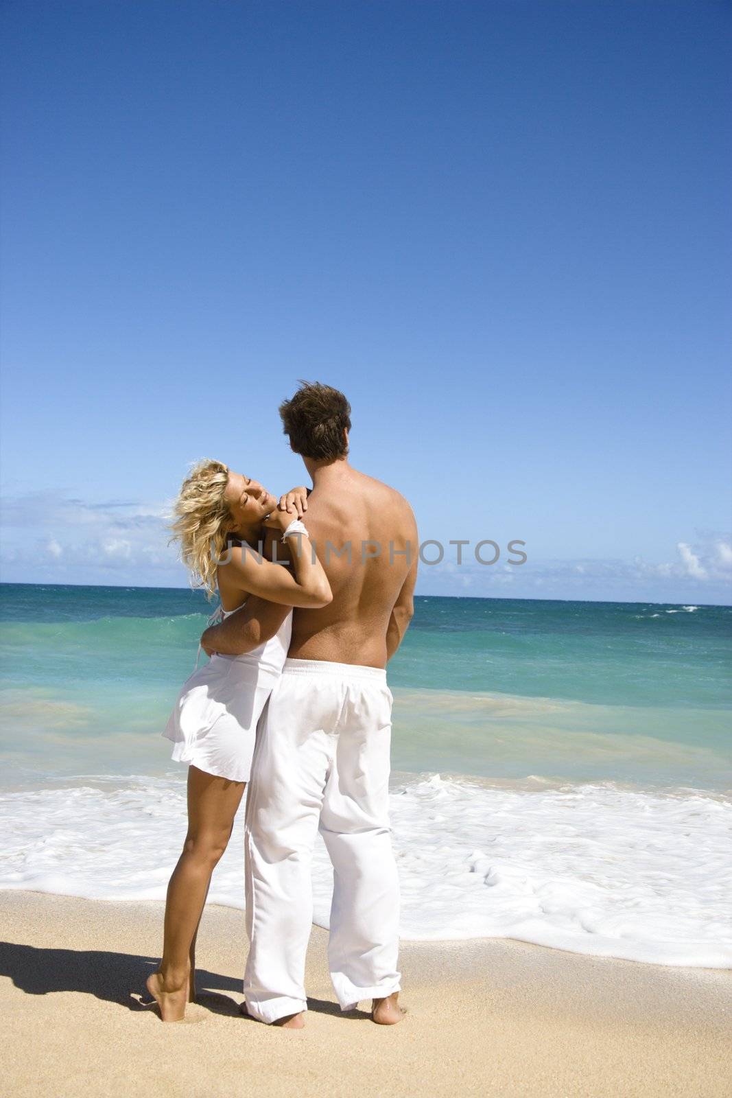 Attractive couple standing on Maui, Hawaii beach holding eachother.