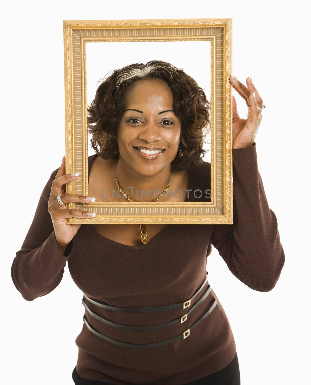 Woman holding empty frame around head smiling.