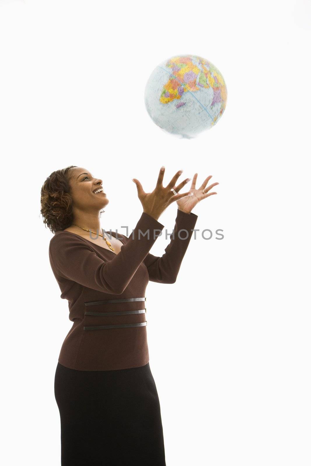 Woman throwing world globe into air and smiling.