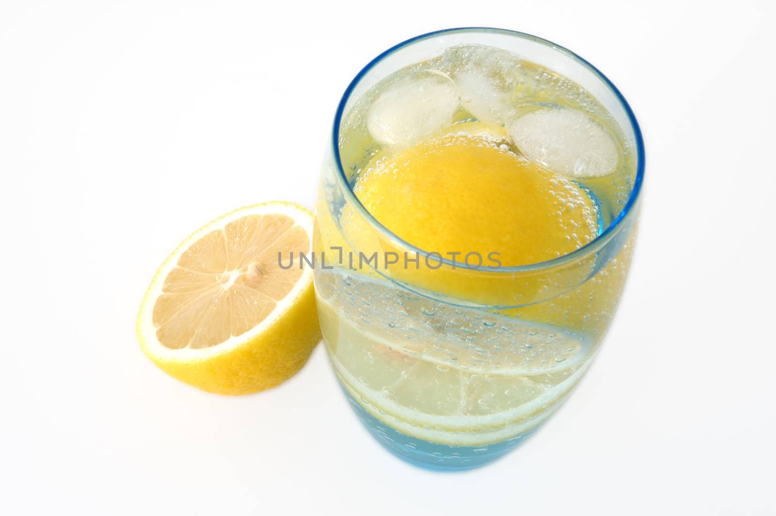 Lemon in glass with mineral water and ice.