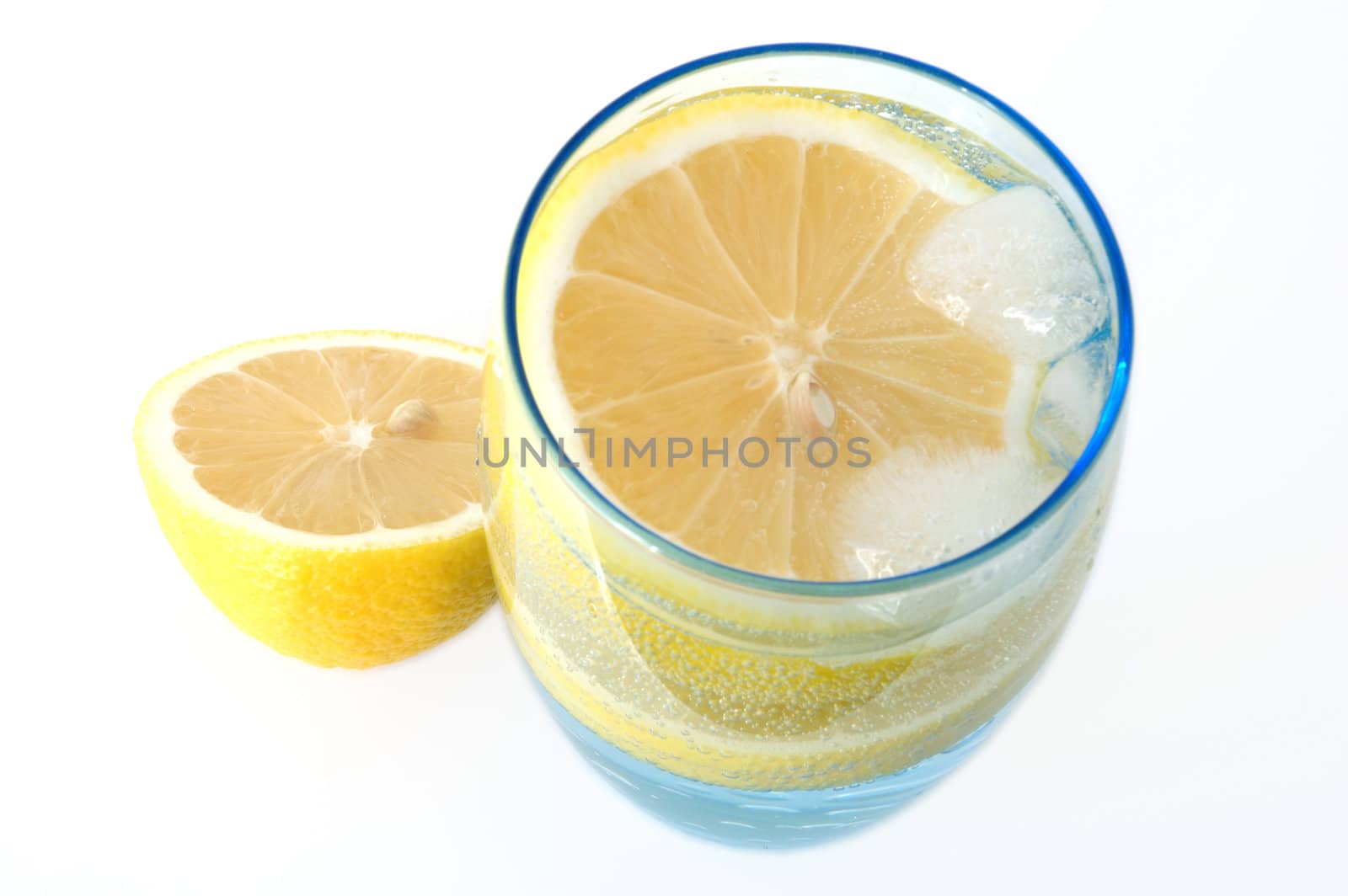 Lemon in glass with mineral water and ice.