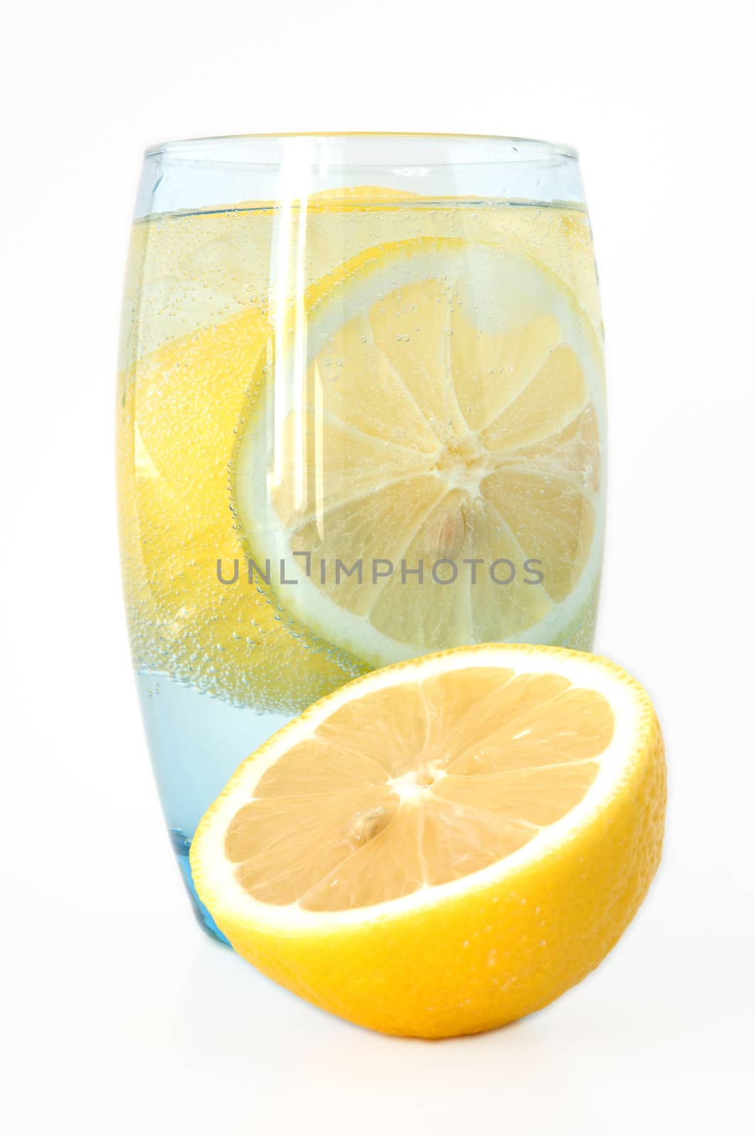 Lemon in glass with mineral water and ice.