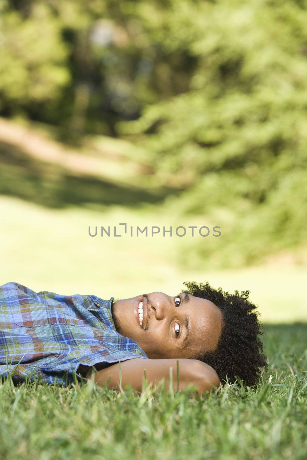 Portrait of man lying in grass in park smiling.