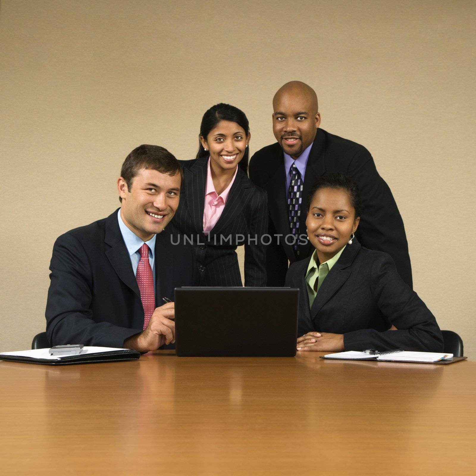 Businesspeople gathered around laptop computer smiling.