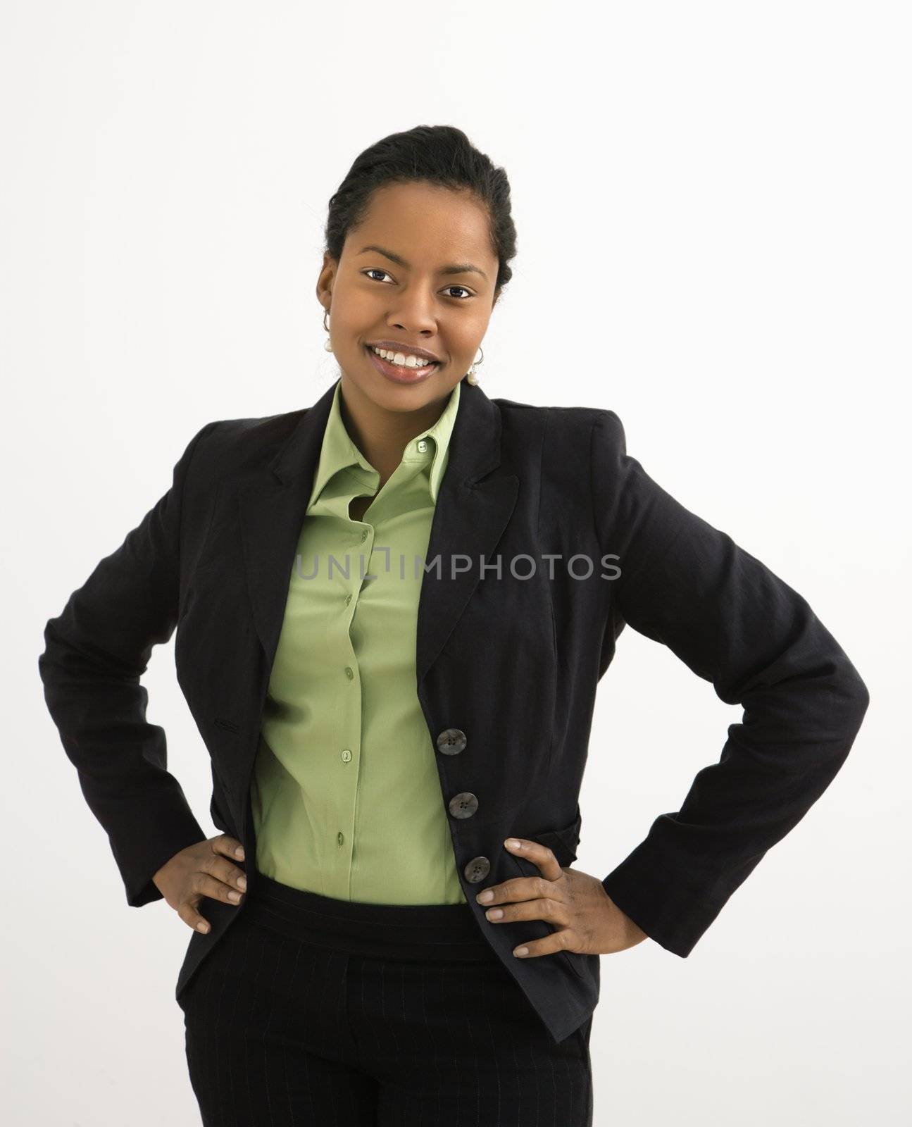 Portrait of smiling businesswoman with hands on hips against white background.