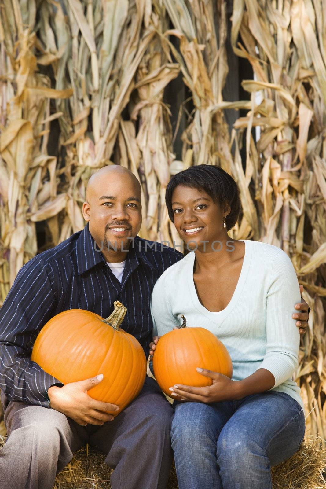 Couple holding pumpkins. by iofoto