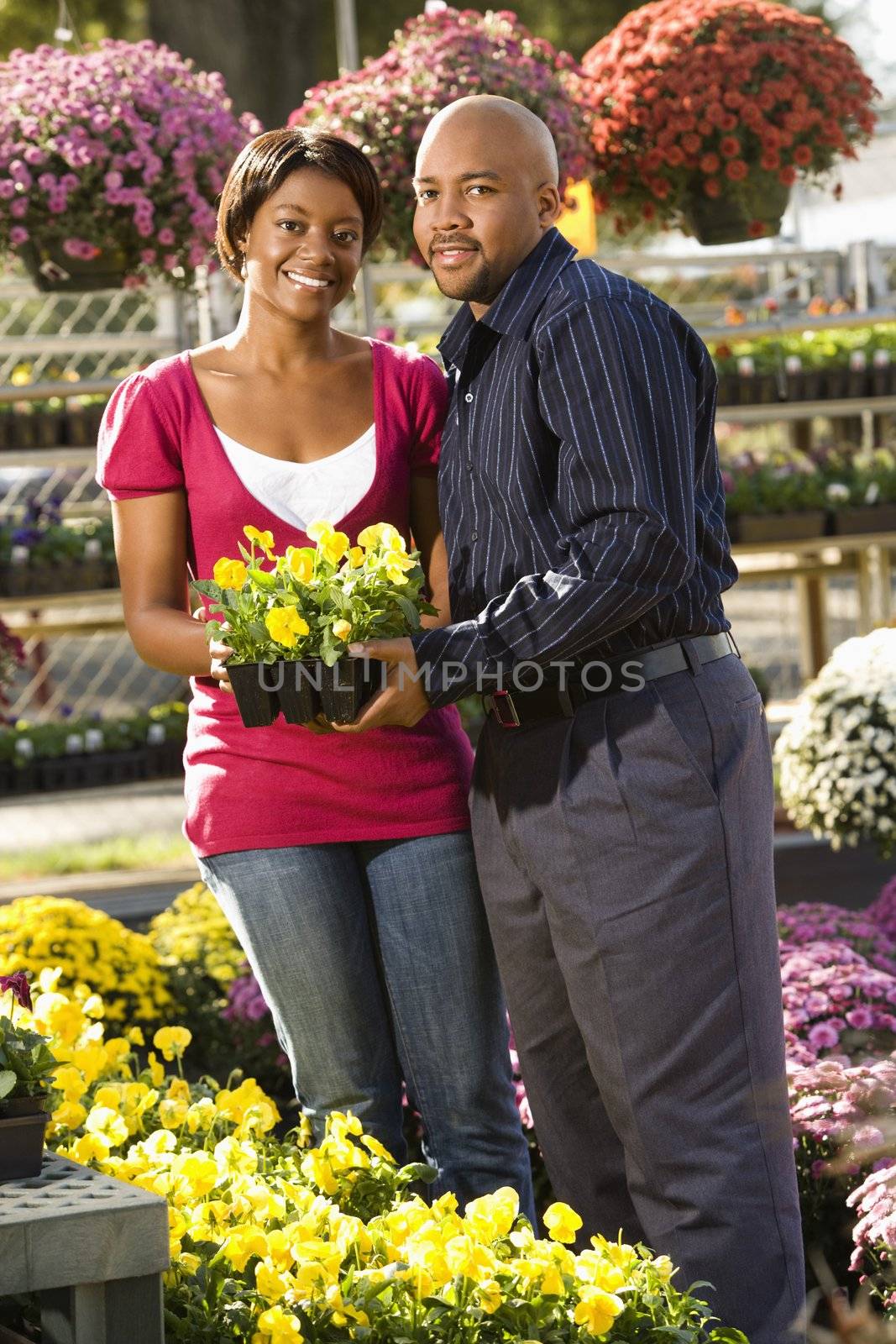 Happy smiling couple picking out flowers at outdoor plant market.