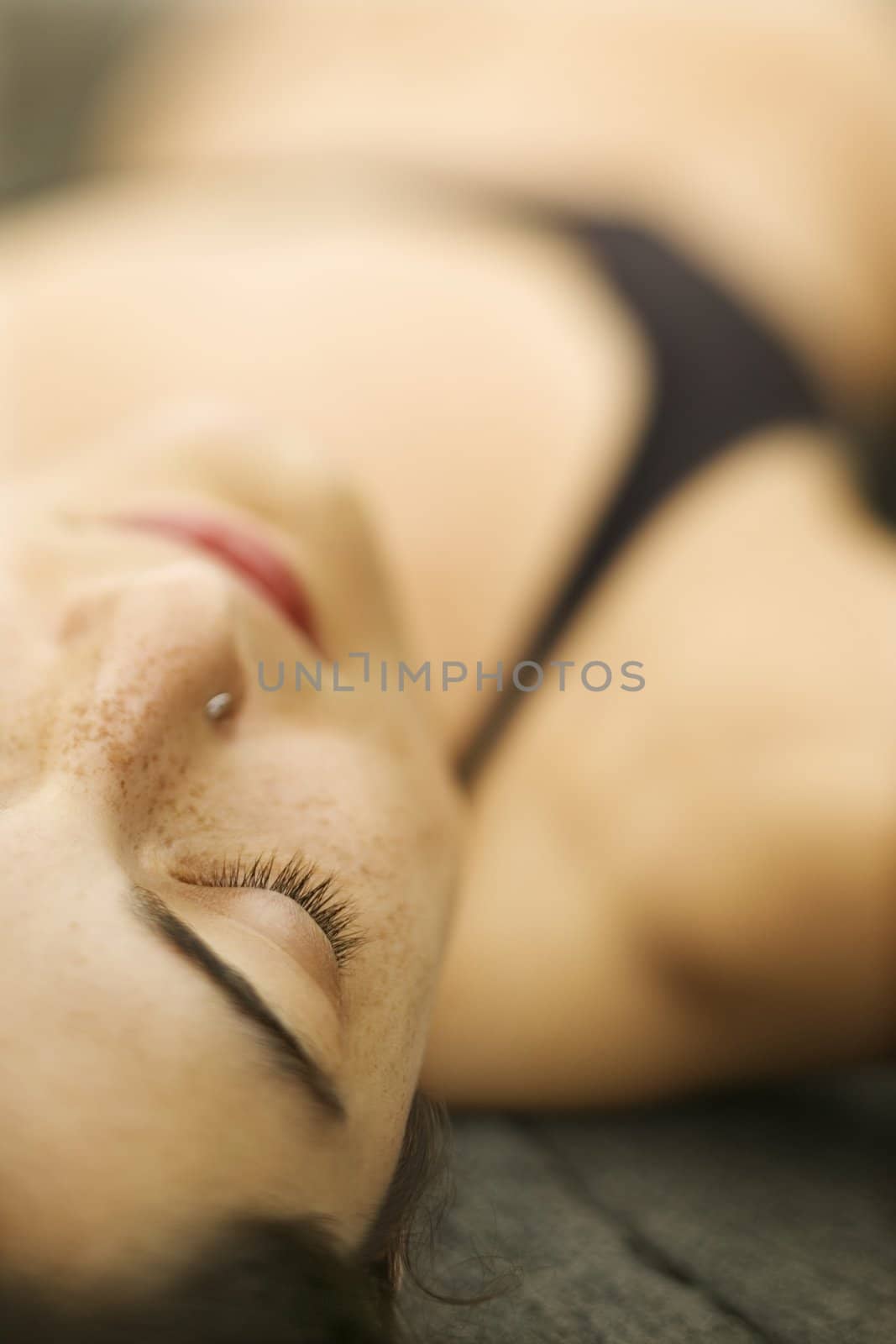 Selective focus close up of Caucasian young woman lying on rock.