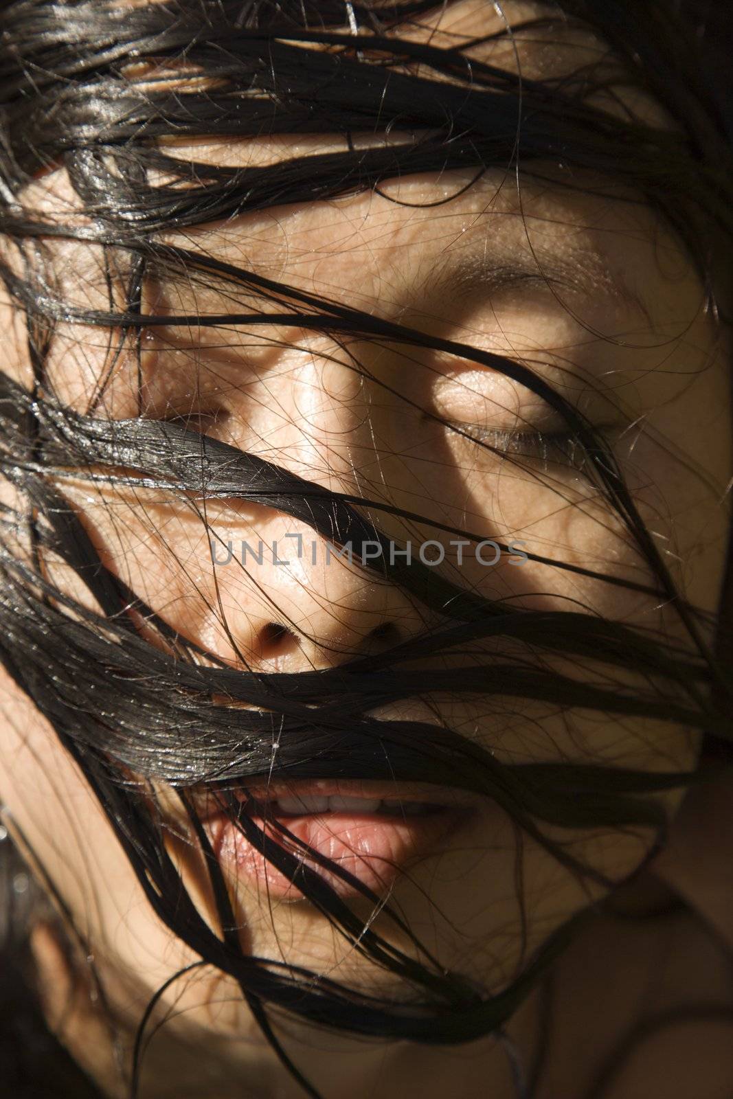 Mid-adult Asian female's face with we hair.