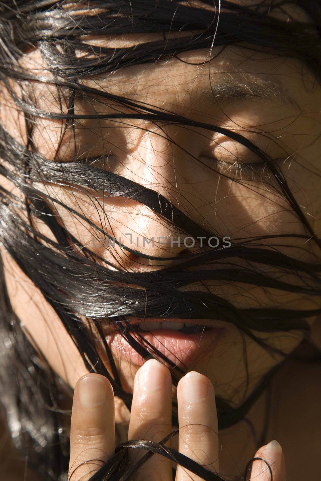 Close-up of mid-adult Asian female's face with wet hair.