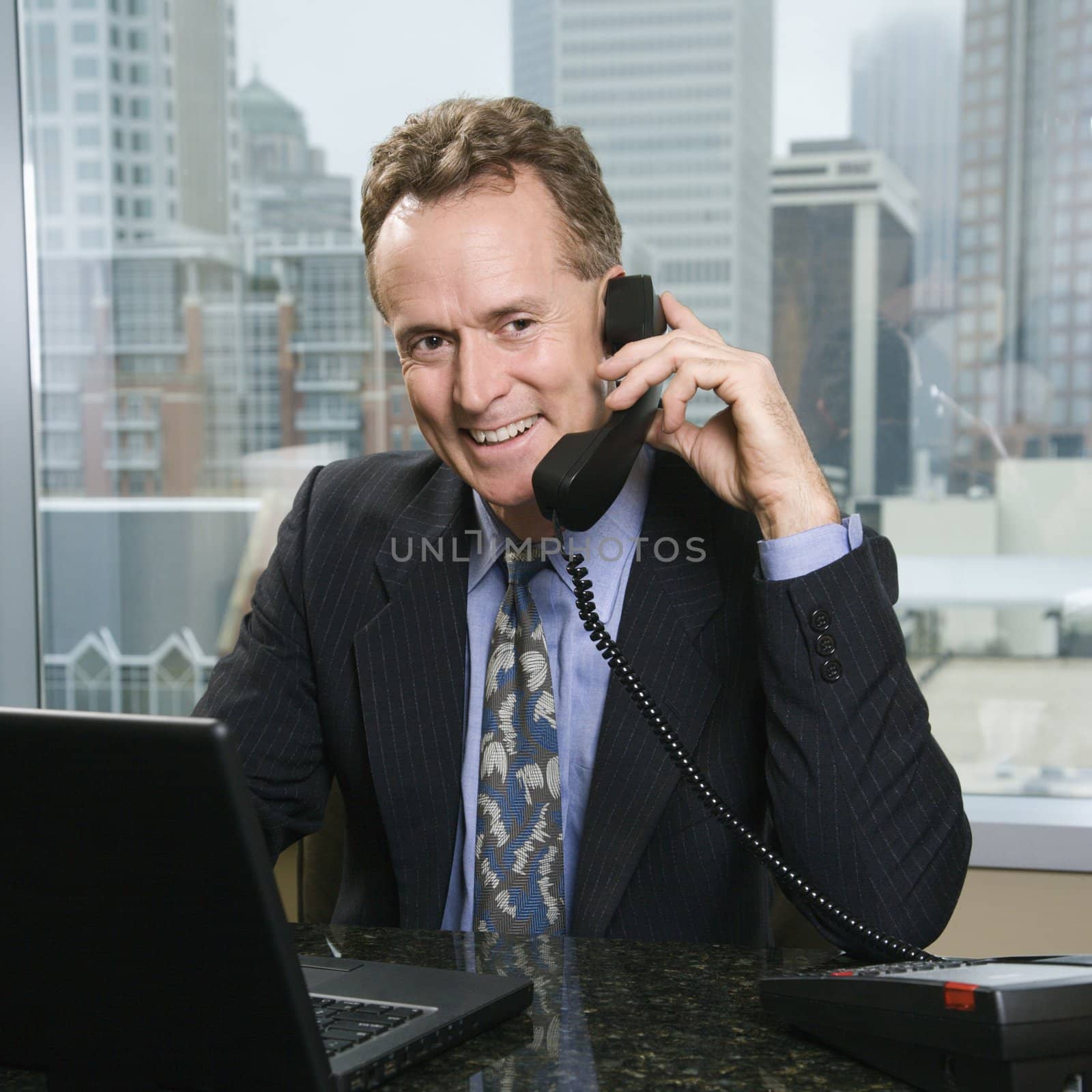 Businessman on phone in office. by iofoto