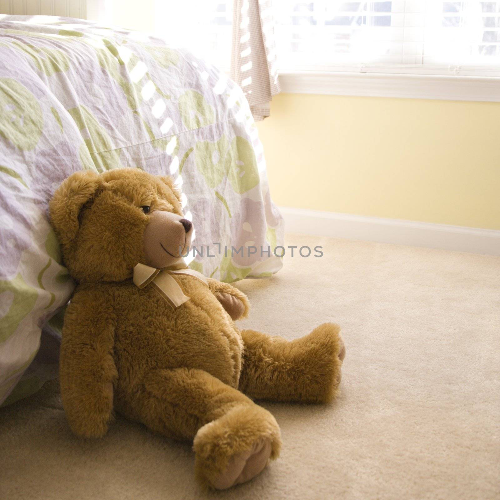 Plush brown teddy bear on bedroom floor.