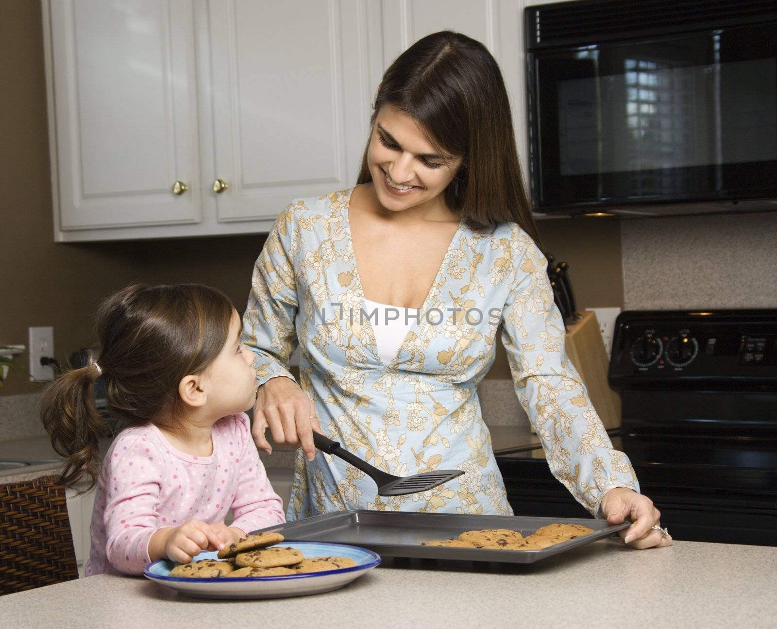 Caucasian mother and daughter with cookies.