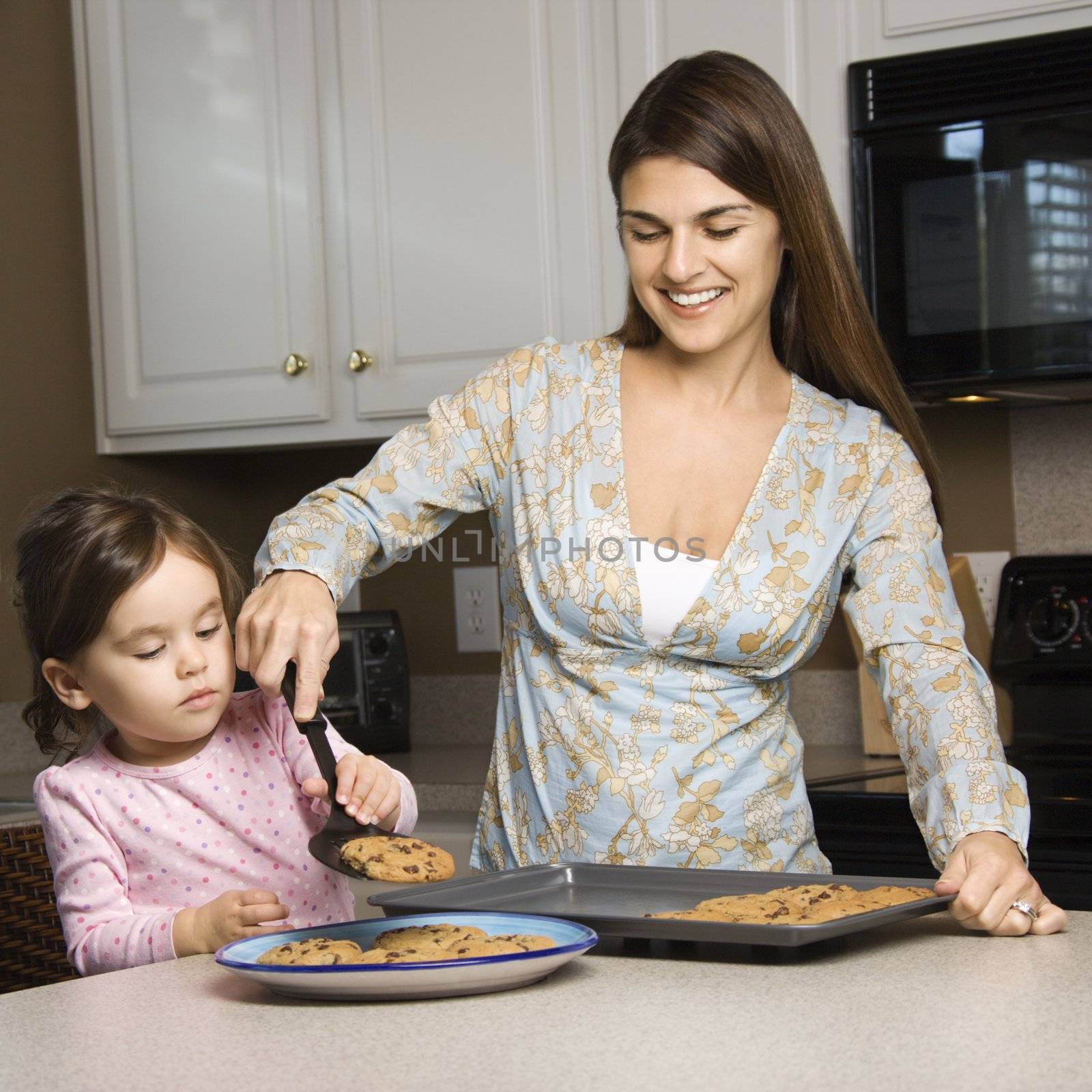 Caucasian mother and daughter with cookies.