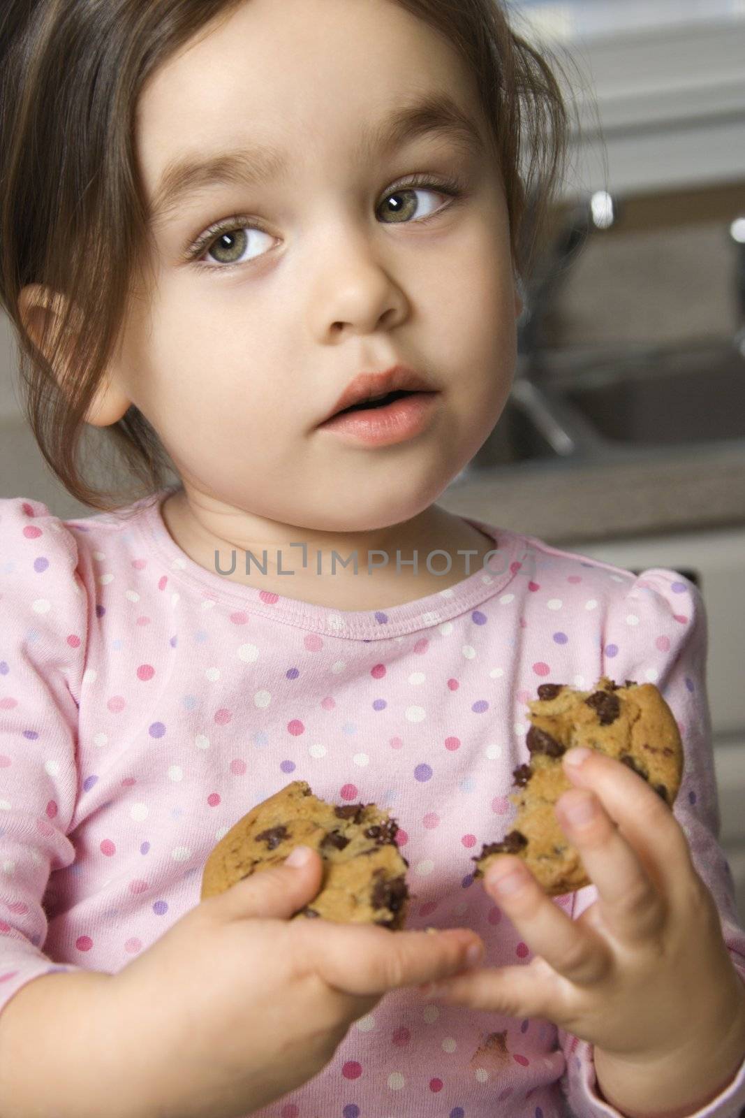 Caucasian girl eating chocolate chip cookie.