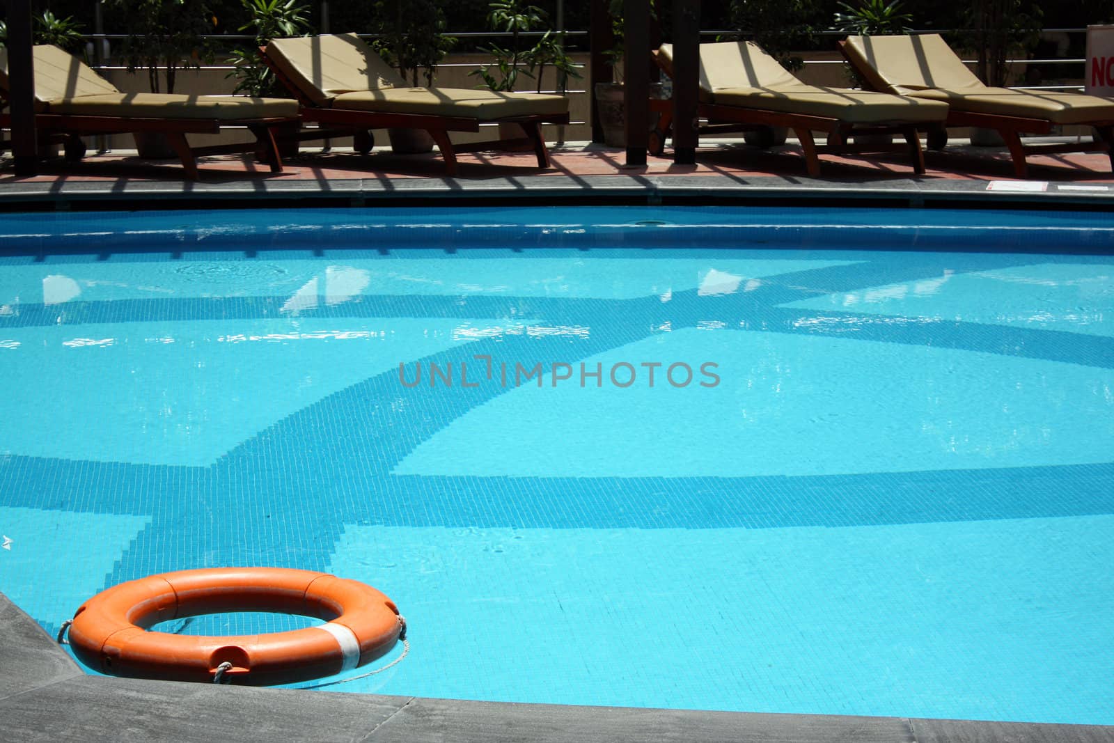 A orange rescue tube lying in a beautiful swimming pool.