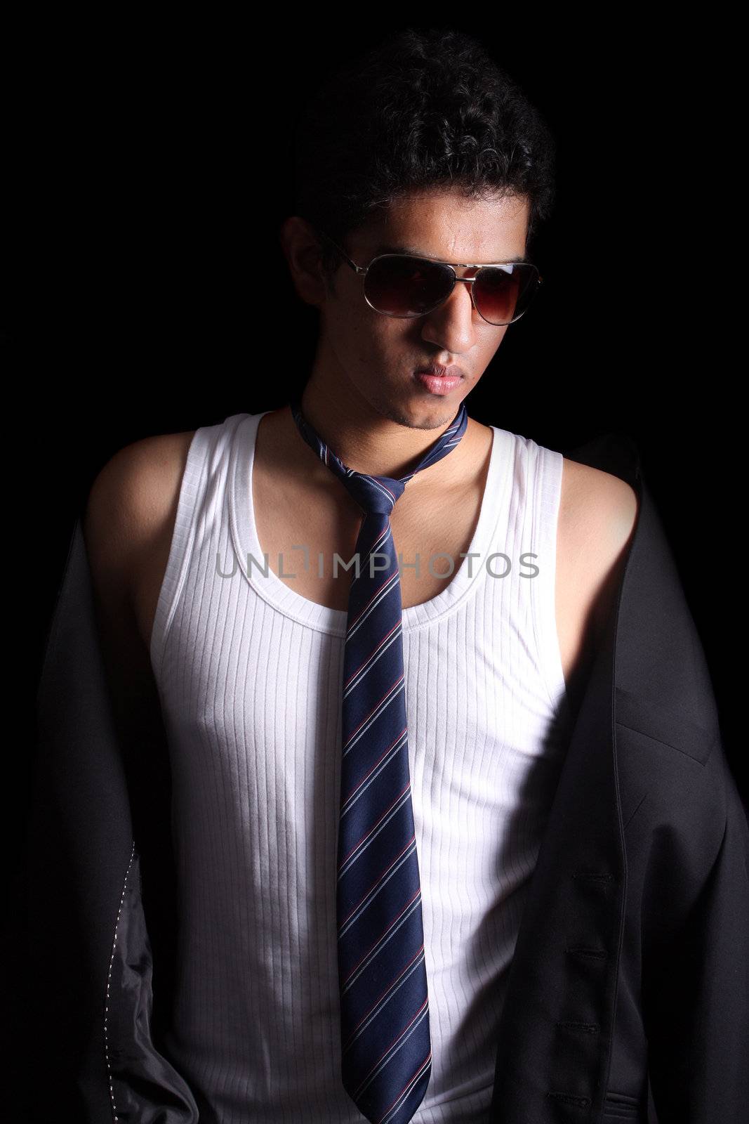 A handsome Indian guy modeling on a black studio background.