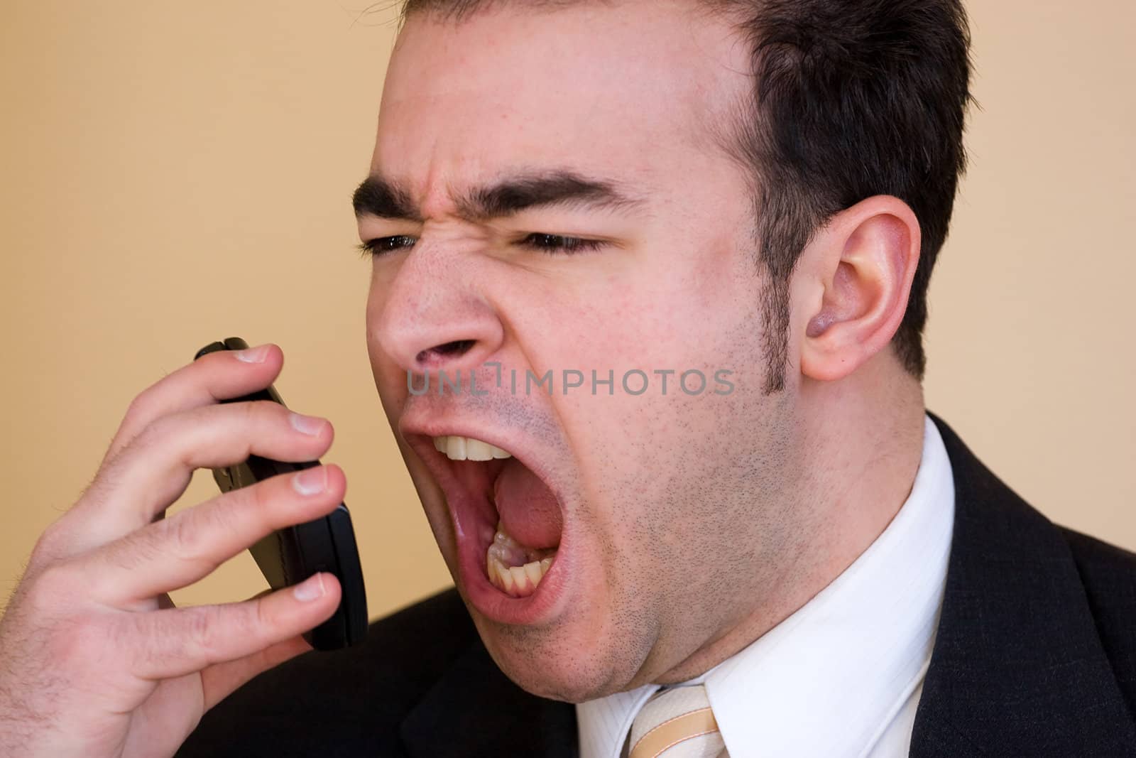 A business man is furiously screaming into his cell phone.