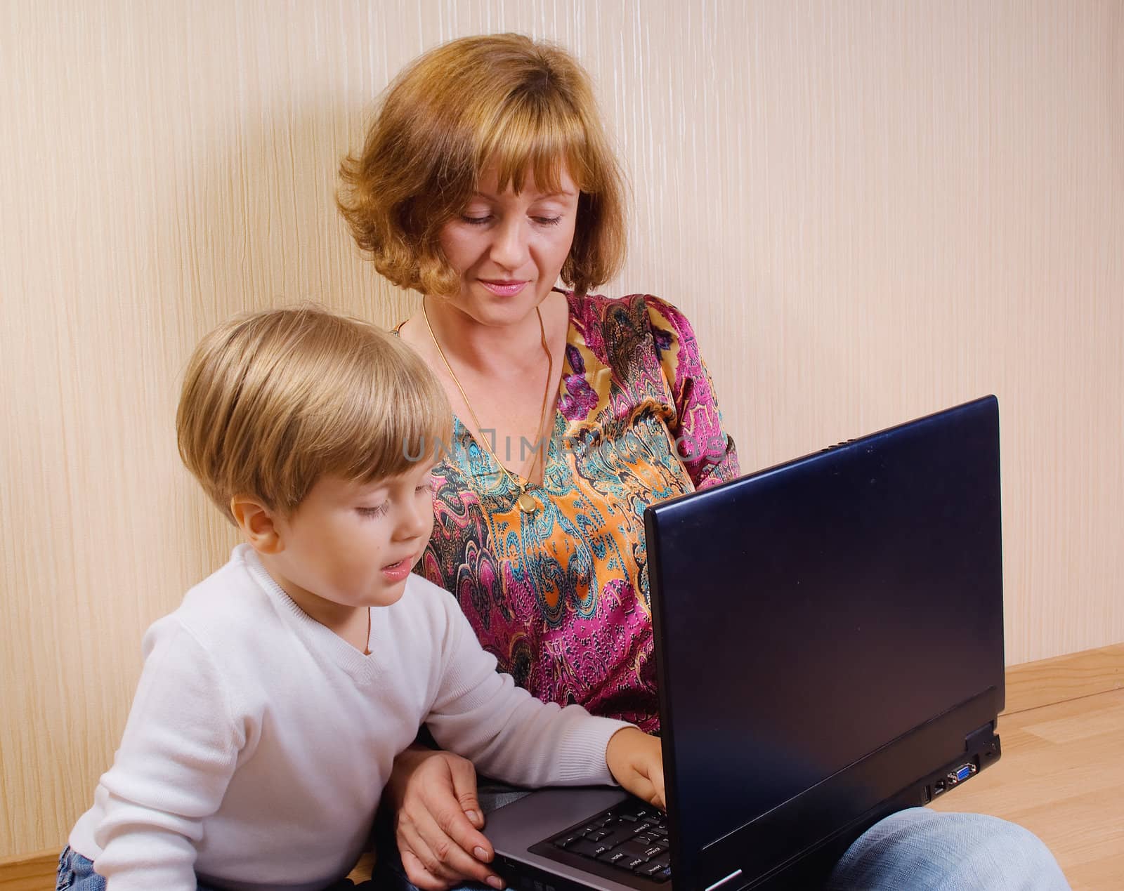 Mother and her son siting on a floor with the computer