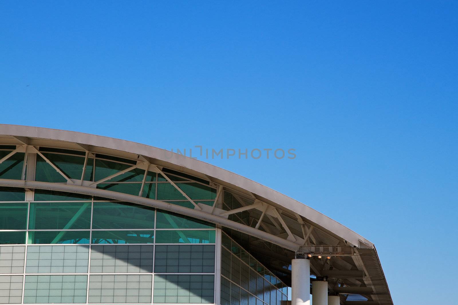 Arched roof sports complex building aginst a cloudless blue sky